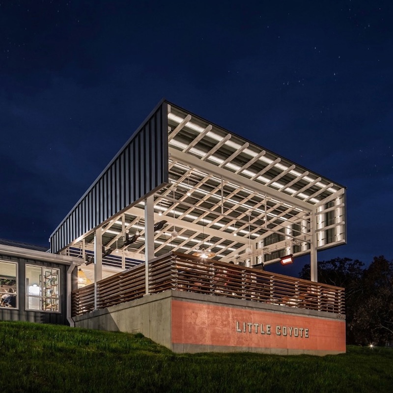 Exterior view of Little Coyote restaurant in Chattanooga TN at night, featuring its signature covered patio and modern design